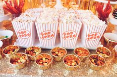 popcorn buckets are lined up on a table with other snacks and condiments