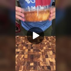 a person holding a bowl with food in it on top of a wooden countertop