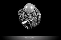 Ayala 7 Rows Pearl Cocktail Statement 4 Carat Cubic Zirconia Ring. This Art Deco Fashion style is created with Genuine Rhodium Plated, Faux Shell Pearl Center Stone and 7 Rolls Round Cut Cubic Zirconia Pave Setting Polished into a Lustrous Silvertone Finish. This ring will make a wonderful addition to any collection. Item: BSJ-CR107023R01 Plating: Silvertone Rhodium Plated Base Metal: Lead Free Alloy (Brass) Pearl Size: 12mm Pearl Color: White Gemstone: Grade AAAAA Cubic Zirconia Gemstone Cut Gr Deco Fashion, Ring Pearl, Pearl Engagement Ring, Celebrity Jewelry, Vintage Cocktail Ring, Cubic Zirconia Jewelry, Cz Jewelry, Couture Jewelry, Cubic Zirconia Rings