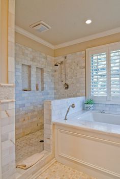 a large white bath tub sitting next to a window with shutters on the windowsill