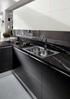 a black and white kitchen with marble counter tops, stainless steel sink and dishwasher