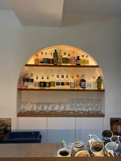 the shelves are filled with liquor bottles and empty glasses on top of them, along with cups in front of them