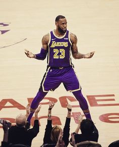 a man standing on top of a basketball court with his hands up in the air