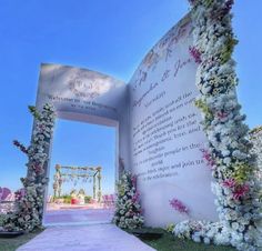 an archway decorated with white flowers and greenery