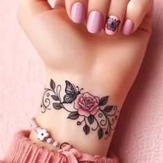 a woman's hand with a pink manicure and flower tattoo on the wrist