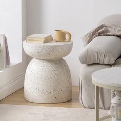 a table with a cup on it next to a chair and pillows in a room