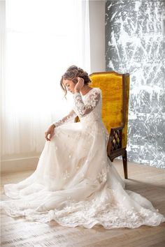 a woman in a wedding dress sitting on a yellow chair with her hands behind her head