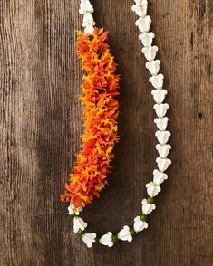 an orange and white flower garland on a wooden surface