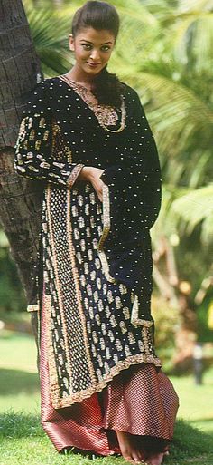 a woman standing next to a palm tree wearing a black and red dress with polka dots on it