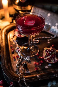 a red drink sitting on top of a metal tray next to candles and other decorations