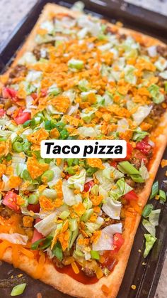 a taco pizza sitting on top of a pan covered in toppings