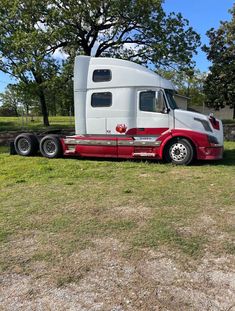 a red and white semi truck parked in the grass