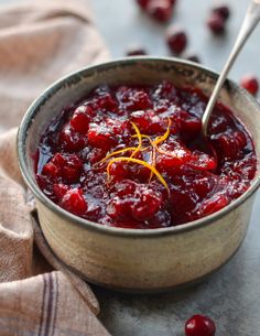 a bowl filled with cranberry sauce on top of a table next to a spoon