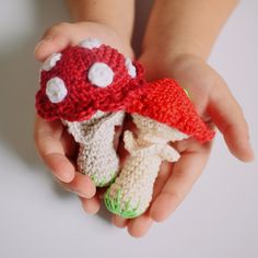 two small crocheted mushrooms are held in the palm of a child's hand