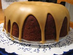 a bundt cake covered in icing on a doily with a blue and white plate