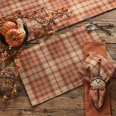 the table is set with plaid napkins and pumpkins