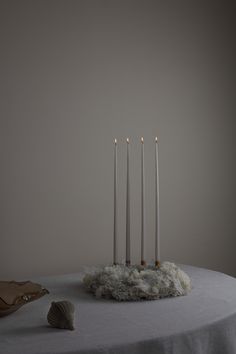 four candles are on top of a table with some white fur around it and one candle is in the middle