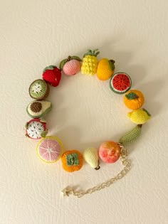 a crocheted bracelet with fruit on it and a chain hanging from the clasp