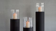 three candles sitting on top of black pedestals