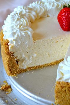 a cheesecake with white frosting and two strawberries on the top is ready to be eaten