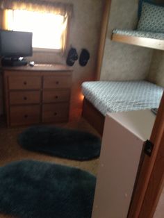 a small bedroom with bunk beds and blue rugs on the floor in front of a window