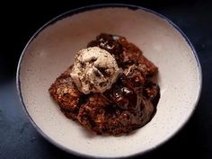 a white bowl filled with ice cream and chocolate cake dessert on top of a table