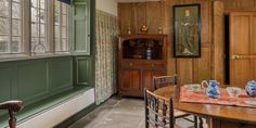 a table and chairs in a room with wood paneling on the walls, along with an old china cabinet