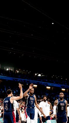 the men are playing basketball against each other in front of an arena full of people