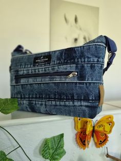 a blue purse sitting on top of a white shelf next to a green leafy plant