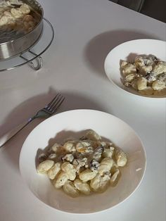 two white bowls filled with macaroni and cheese on top of a table next to a silver tray