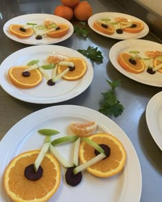 several plates with orange slices cut into the shape of people's faces on them