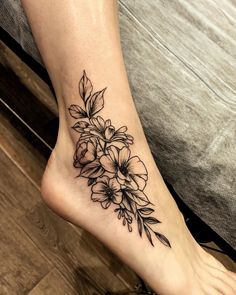 a woman's foot with flowers and leaves tattoo on the left side of her leg