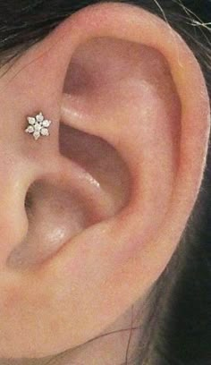 a close up of a person's ear with a small white flower on it