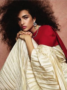 a woman with long hair wearing a white dress and red cape over her shoulders, posing for the camera