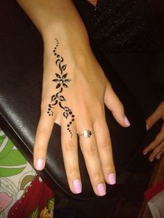 a woman's hand with a henna tattoo on her left wrist and finger