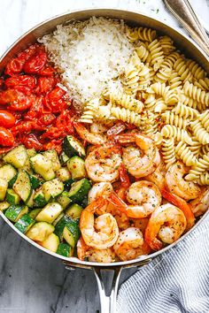 a pan filled with pasta, vegetables and shrimp