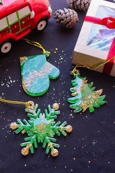 christmas ornaments are sitting on a table next to a gift box and pineconi