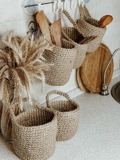 three woven baskets with spoons and spatulas hanging from hooks on the wall