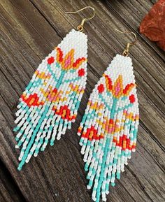 two pairs of beaded earrings sitting on top of a wooden table