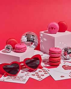 pink macaroons, heart - shaped sunglasses and disco balls on red background