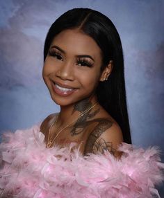 a woman with tattoos and pink feathers on her chest smiling at the camera while posing for a photo