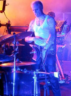 a man with tattoos playing drums on stage