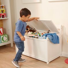 a little boy standing in front of a toy chest