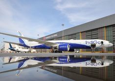 an airplane is parked in front of a building with its reflection on the tarmac