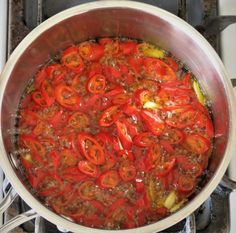 a pot filled with lots of red peppers on top of a stove burner next to an oven