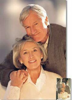 an older man and woman are smiling for the camera, with their arms around each other