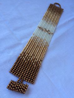 a beaded bracelet is laying on top of a white sheet with brown beads in it