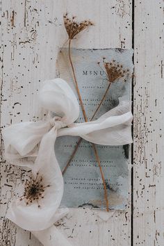 a piece of paper with some flowers tied to it on top of a wooden board