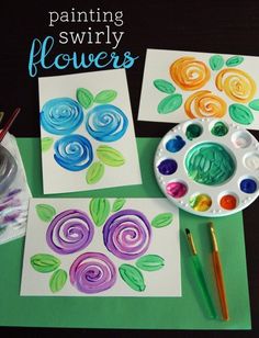 painting swirly flowers with watercolors on paper next to a brush and palette