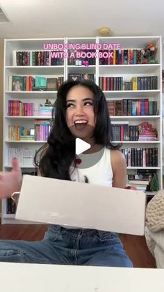 a woman holding up a book in front of a bookshelf